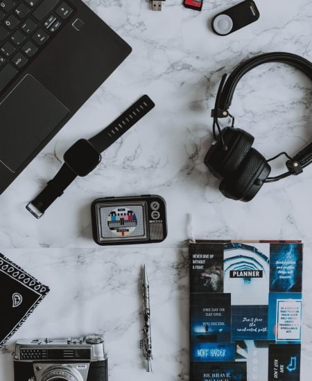 A flat lay composition of digital devices and a vintage camera on a marble surface.